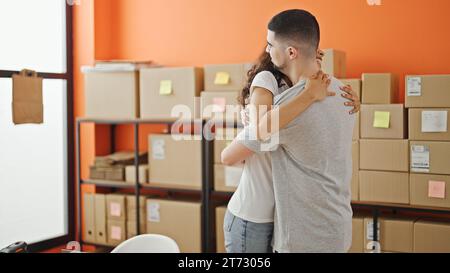 Two smiling workers, man and woman, sharing a heartfelt hug in the office, embodying team spirit Stock Photo