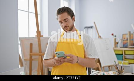 Young hispanic man artist using smartphone at art studio Stock Photo