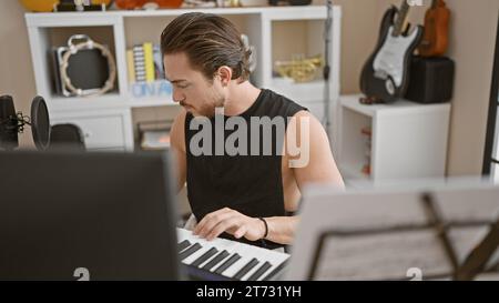 Young hispanic man musician playing piano at music studio Stock Photo