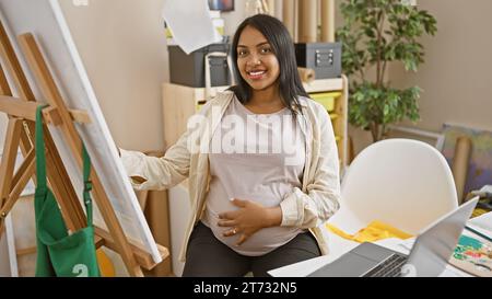 Confident and smiling young pregnant artist enjoys drawing in art studio Stock Photo