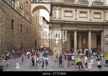 Florence, Italy: Uffizi and side of Palazzo Vecchio in Piazza della Signoria, with tourists and statue street performer Stock Photo