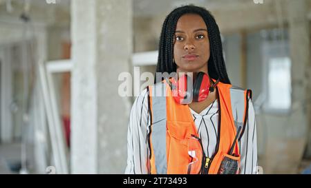 African american woman builder smiling confident wearing headphones with arms crossed gesture at construction site Stock Photo
