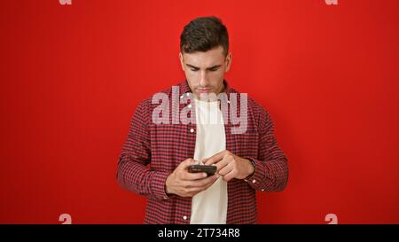 Young hispanic man using smartphone over isolated red background Stock Photo