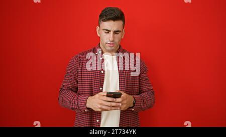Young hispanic man using smartphone over isolated red background Stock Photo