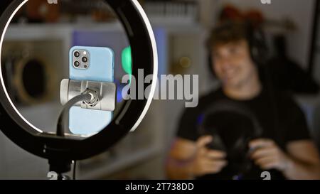 Handsome hispanic man caught in thrilling night-time gaming stream, engrossed in virtual conversation amidst the glow of his gaming room, headphones r Stock Photo