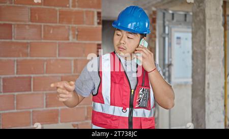 builder talking on smartphone at construction site Stock Photo
