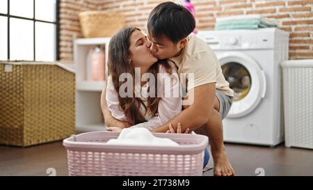 Man and woman couple folding clothes hugging and kissing at laundry room Stock Photo