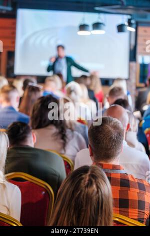 Back view of multiethnic business professionals listening to speaker giving presentation in conference hall Stock Photo