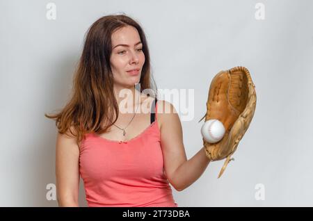 Woman in pink T-shirt catches ball with a baseball glove. Smile on face. Stock Photo