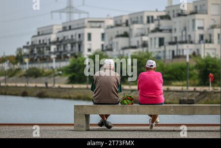 Gelsenkirchen, North Rhine-Westphalia, Germany - senior citizens sitting on a park bench at the marina in the new city quarter Graf Bismarck, apartmen Stock Photo