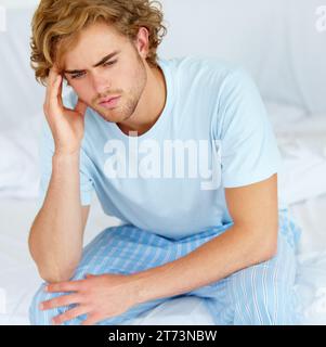 Stress, thinking and exhausted with a man on his bed in the morning to wake up feeling moody. Depression, mental health or burnout with a tired young Stock Photo