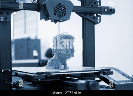 Model of toy lion printed on 3D printer from melted plastic blue color on desktop of 3D printer. Concept 3D printer, 3D printing, modeling prototyping three dimensional object. Innovative production Stock Photo