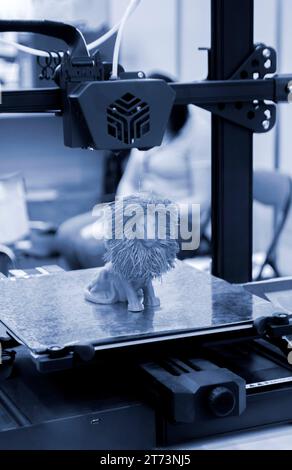 Model of toy lion printed on 3D printer from melted plastic blue color on desktop of 3D printer. Concept 3D printer, 3D printing, modeling prototyping three dimensional object. Innovative production Stock Photo