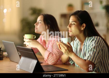 Two tele workers relaxing drinking coffee in the night at home Stock Photo