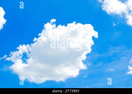 A vibrant blue sky serves as a beautiful backdrop for large, puffy white clouds on a sunny, clear day. Stock Photo