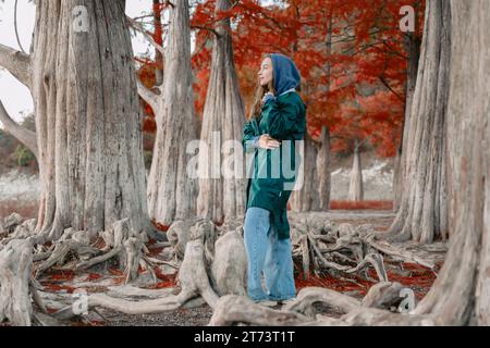Woman in a jacket walking among trees in park. Portrait of people in park in autumn. Stock Photo