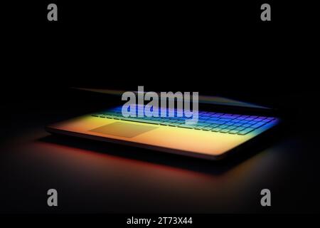 half closed laptop on dark table with colourful light reflection on keyboard Stock Photo