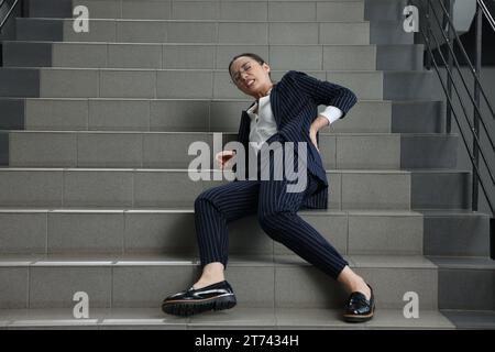 Woman fallen down stairs suffering from pain in back indoors Stock Photo