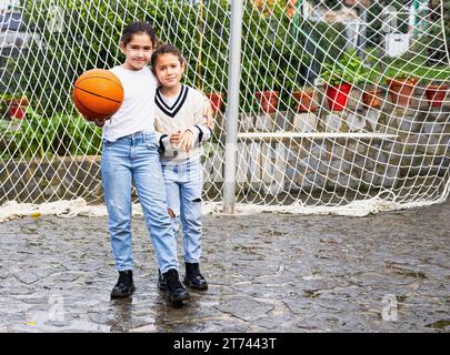 Two girls hugging each other after playing basketball in the backyard at home Stock Photo