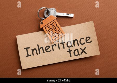 Card with phrase Inheritance Tax and key with house shaped key chain on brown background, top view Stock Photo