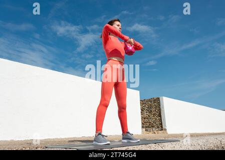 Fit woman doing exercises with kettlebell outside Stock Photo