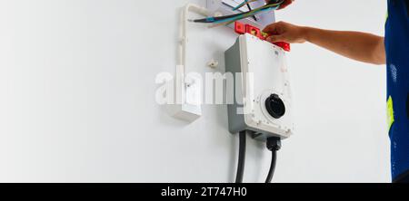 Certified male Electrician Installing Home EV Charger Stock Photo