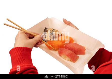 Food delivery. A box with sushi rolls in woman hands isolated on a white background. Stock Photo