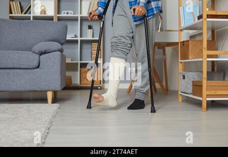 Man with fractured leg in plaster cast standing with crutches Stock Photo