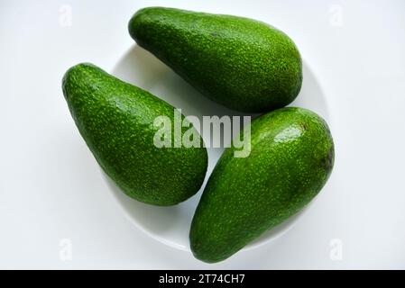 Ripe juicy avocado fruit on a white background. Vegetarian vegetables. Green fruits. Stock Photo