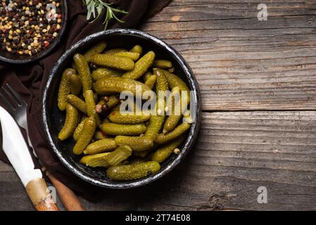 Pickled cucumbers in the black bowl over wooden background Stock Photo