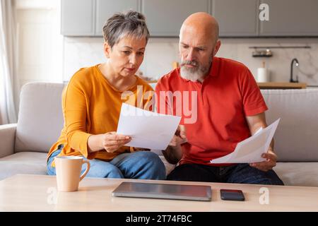 Stressed Senior Couple Checking Financial Papers And Planning Budget At Home Stock Photo