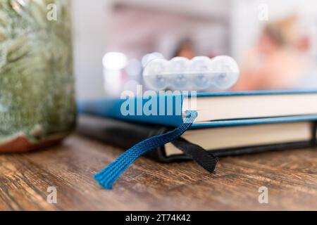 Close up of two closed notebooks with ribbon bookmarks and a green mug on a wooden table at a coffee shop with bokeh background. Stock Photo