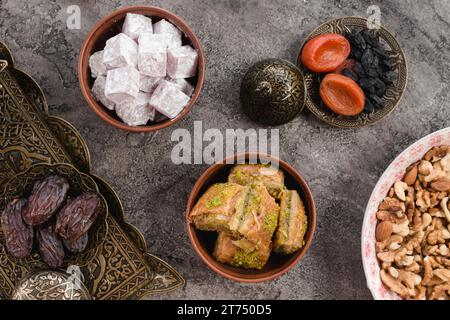 Earthen bowl lukum baklava dates nuts dried fruits gray concrete Stock Photo