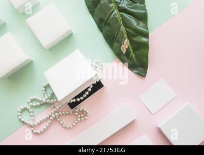 Overhead view pearl necklace golden earrings with white boxes paper background Stock Photo