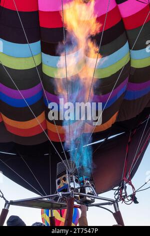 Blue and orange flames from a burner feed hot air into the envelope of an inflating multi-color balloon at the Albuquerque International Ballon Fiesta Stock Photo