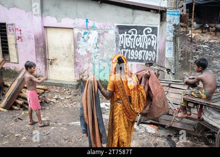 Woman with washed clothes and two boys, Tejgaon Slum Area, Dhaka, Bangladesh Stock Photo