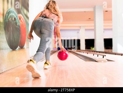 Back view woman throwing bowling ball Stock Photo