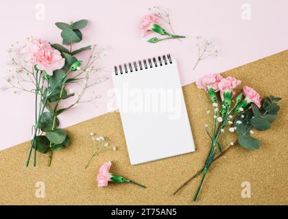 Overhead view spiral notepad surrounded with gypsophila carnation flowers dual pink cardboard background Stock Photo