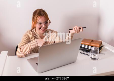 Smiley female teacher using laptop during online class with students Stock Photo