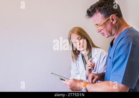 Concentrated doctors using pad device while talking about a patient diagnosis. Stock Photo