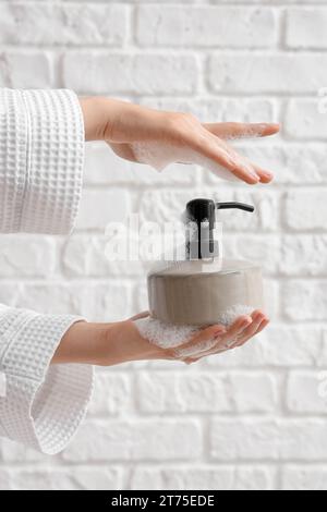 Hands with liquid soap on white brick background Stock Photo