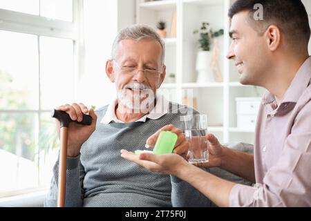 Senior man with his son taking pills at home Stock Photo