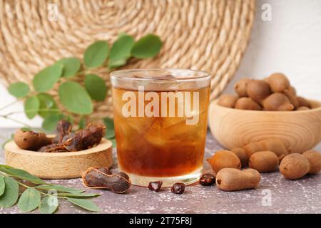 Glass of tasty tamarind drink and fruits on table Stock Photo