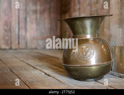 Old copper spittoon on a saloon floor. Stock Photo