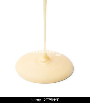 Pouring tasty condensed milk isolated on white Stock Photo