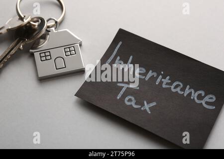 Card with phrase Inheritance Tax and keys with house shaped key chain on grey background, closeup Stock Photo