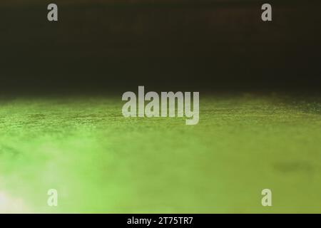 Natural light reflection through green glass onto a wooden surface, creating a captivating interplay of light and shadow. Ideal photo for backgrounds. Stock Photo