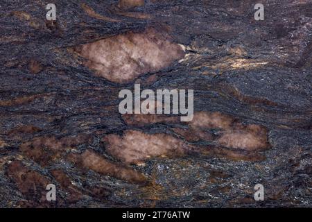 Unique texture of natural granite slab, with dark brown layers of rock that looks like molten lava. Stock Photo