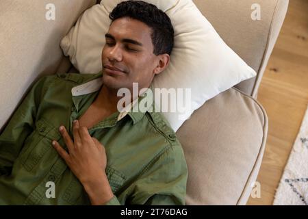 Biracial man lying on sofa and sleeping at home Stock Photo