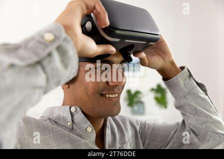 Happy biracial man using vr headset at home Stock Photo